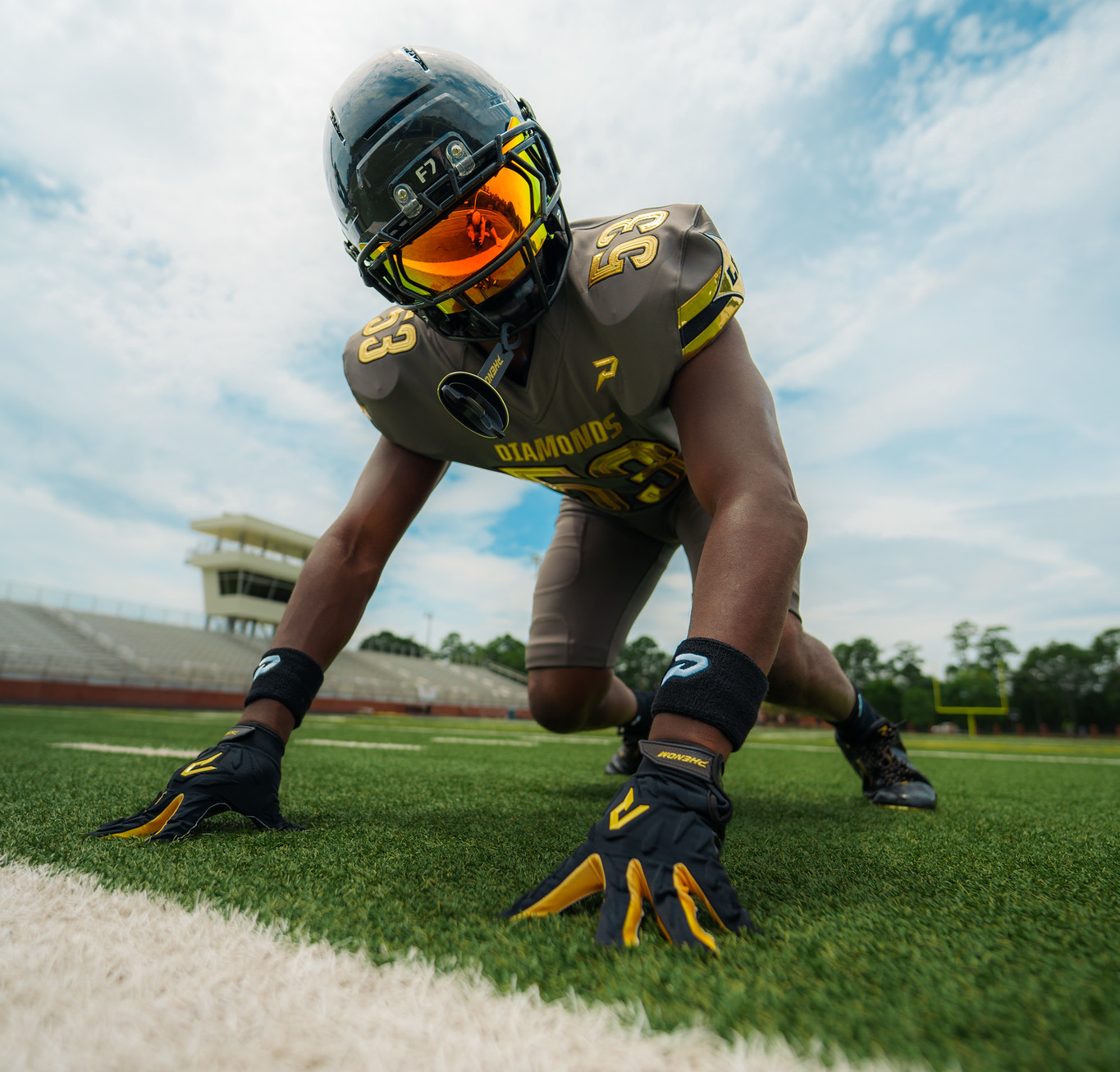 Diamonds player in a Phenom tackle uniform and gloves in a three-point stance